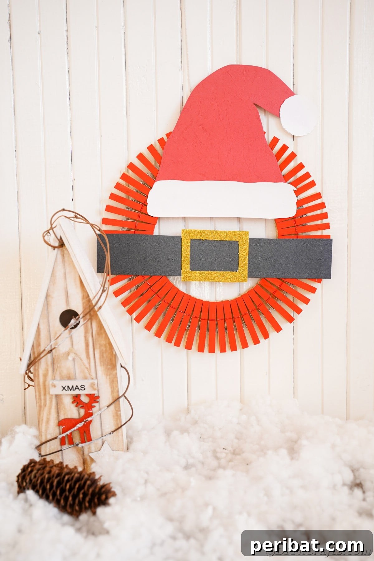 Craft a Delightful Santa Hat Wreath for Christmas 4 Santa hat wreath hanging on a white shiplap wall, showcasing holiday decor.