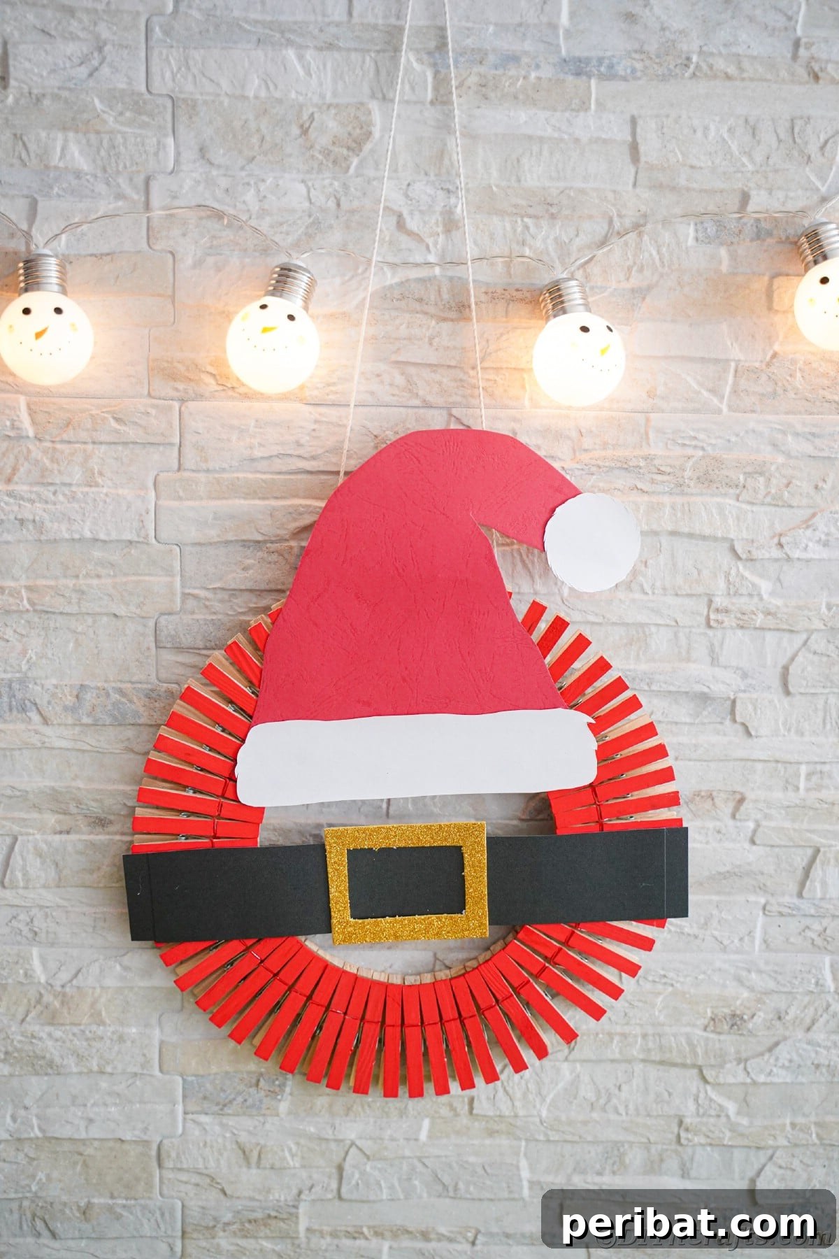 Craft a Delightful Santa Hat Wreath for Christmas 19 Santa hat wreath hanging on a white brick wall, adding a rustic holiday touch.