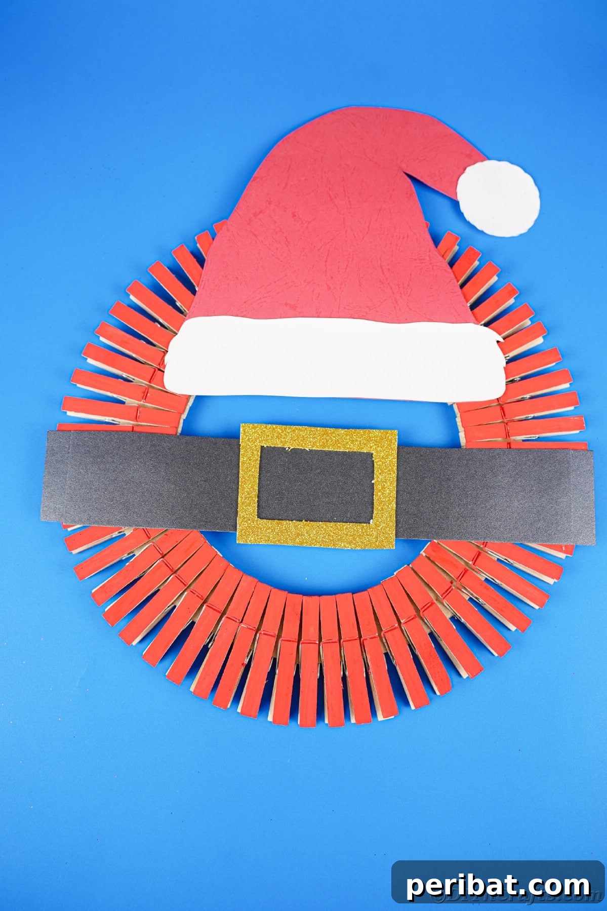 Craft a Delightful Santa Hat Wreath for Christmas 20 Blue background behind a Santa hat wreath, highlighting its festive colors.