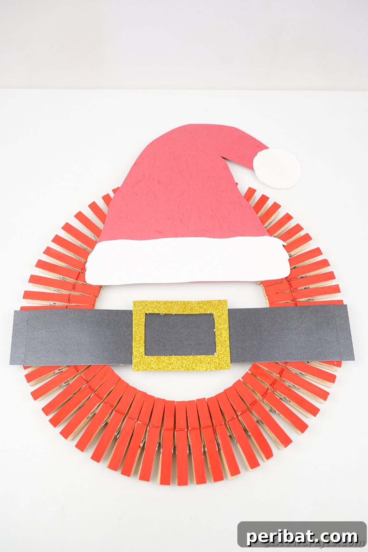 Craft a Delightful Santa Hat Wreath for Christmas 21 Santa wreath hanging on a plain white wall, a charming and simple decoration.