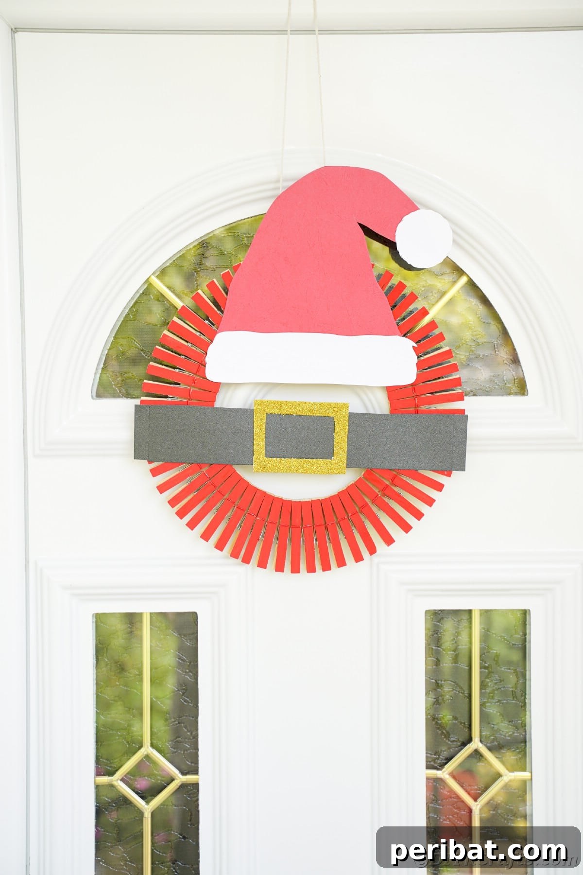 Craft a Delightful Santa Hat Wreath for Christmas 7 Santa hat wreath hanging on a white door with glass panels, a festive welcome.