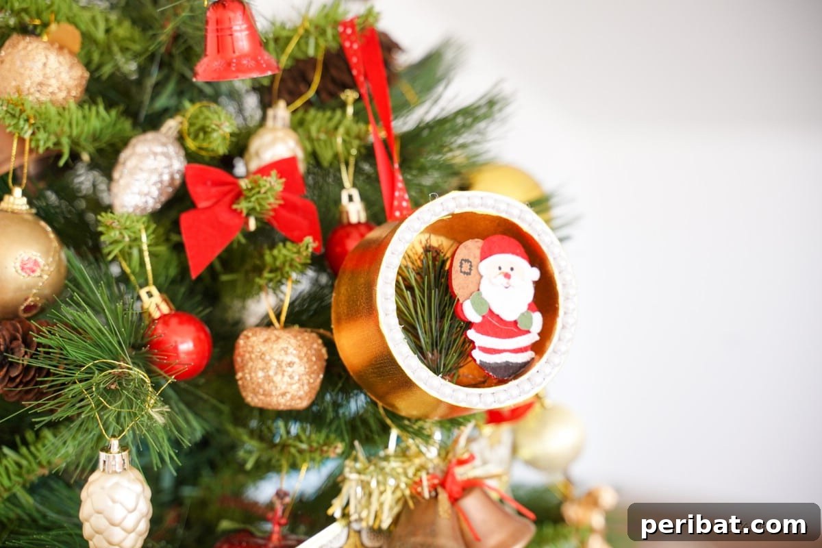 Whimsical Upcycled Santa 3D Christmas Tree Ornament 27 3D diorama craft Christmas ornament hanging on a tree, blending beautifully with other decorations.