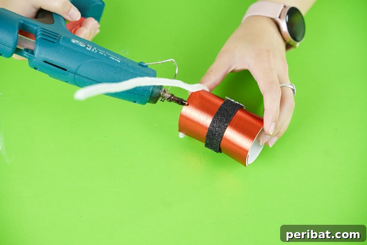 hot glue gun applying pipecleaner to a small Santa craft 