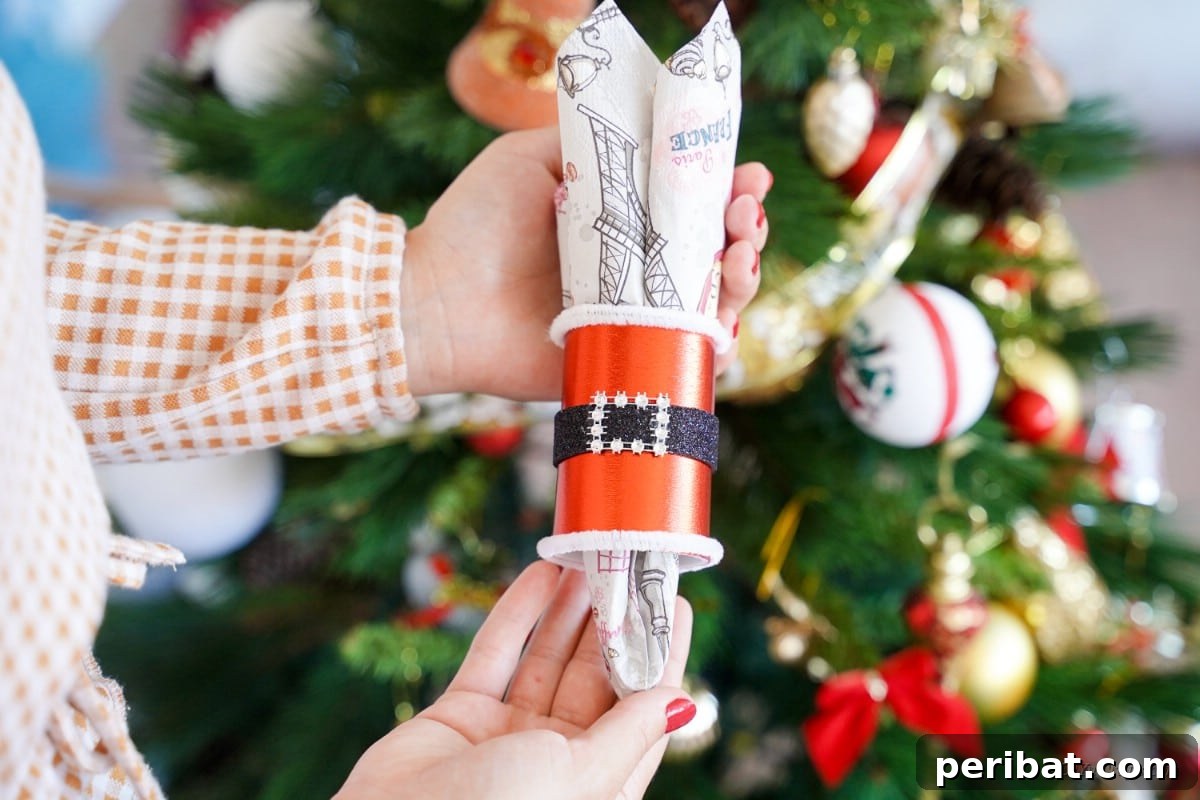 woman holding santa themed napkin ring in front of Christmas tree
