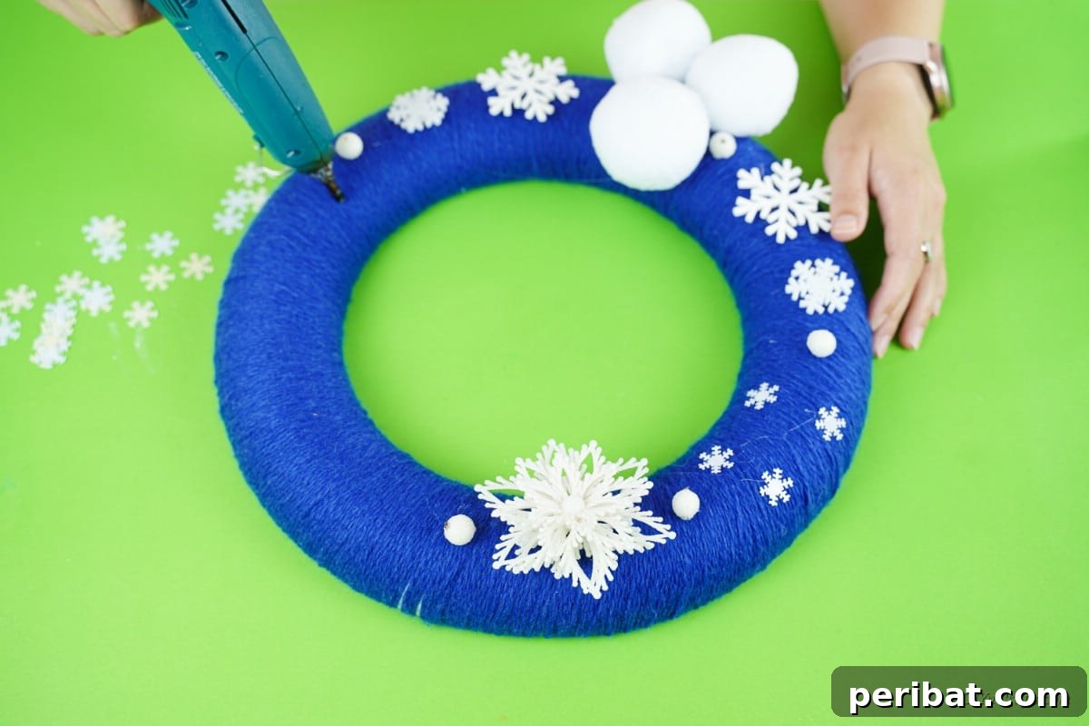 Glistening Snowflake Christmas Wreath 13 Close-up of craft snowflakes being meticulously attached to a vibrant blue wreath, demonstrating the final decorative steps