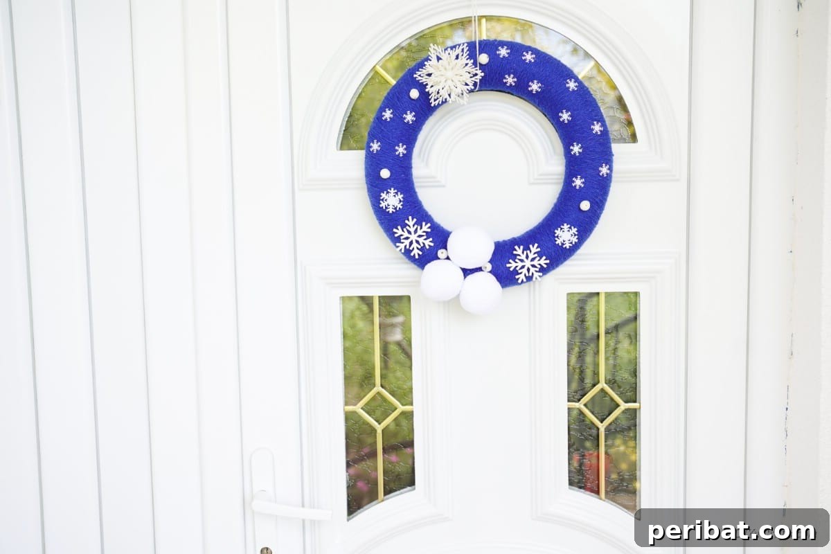 Glistening Snowflake Christmas Wreath 14 Finished blue snowflake wreath gracefully hanging on a front door, creating a welcoming and festive entrance