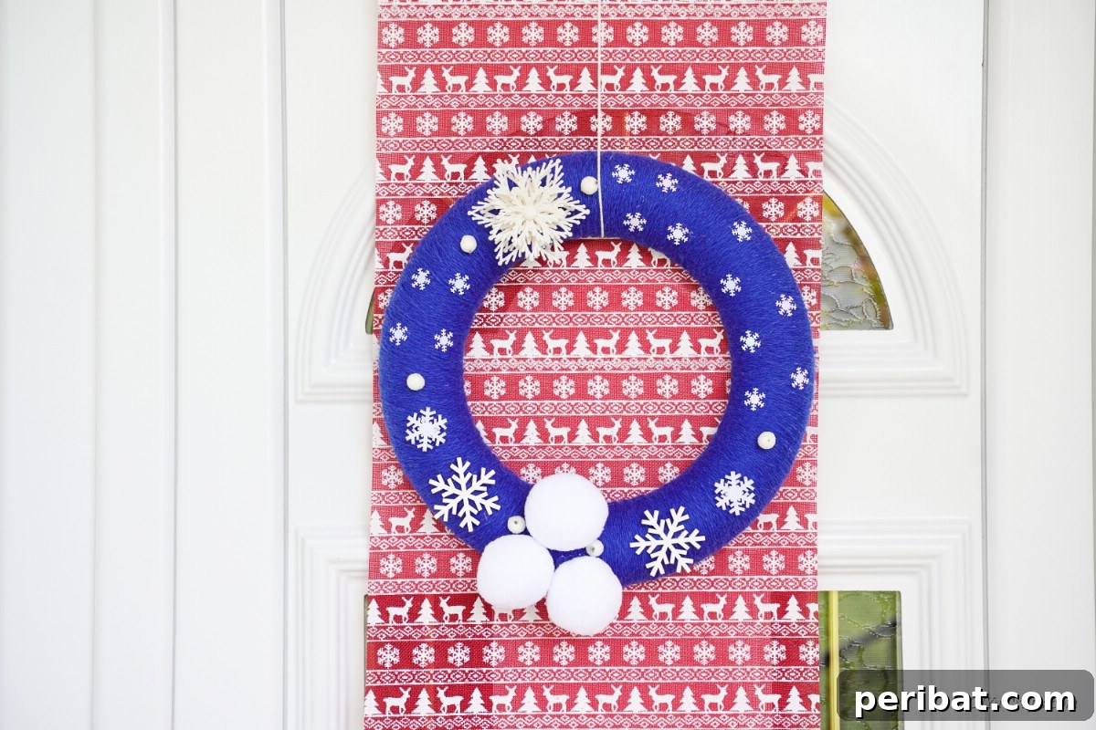 Glistening Snowflake Christmas Wreath 15 Vibrant blue Christmas wreath adorned with snowflakes, displayed elegantly over rich red wrapping paper, creating a striking holiday contrast