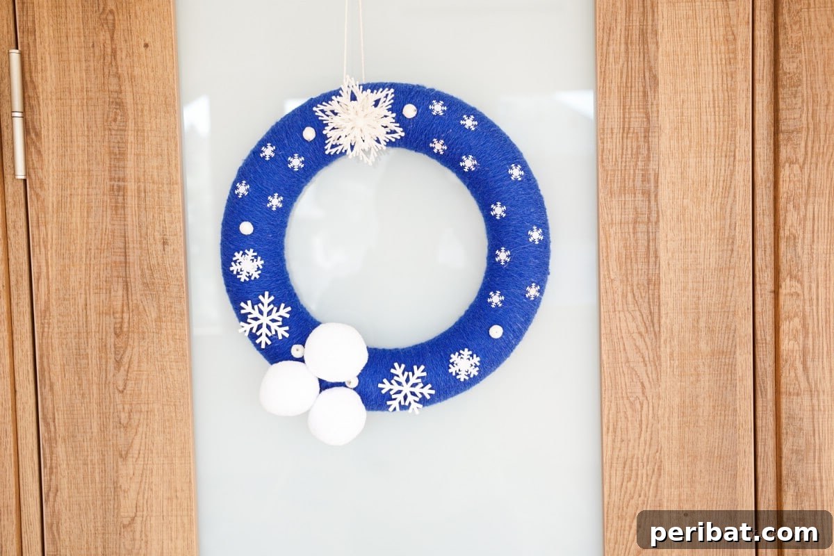 Glistening Snowflake Christmas Wreath 6 Stunning blue and white snowflake wreath elegantly hanging on a glass and wood door, enhancing the home's entrance