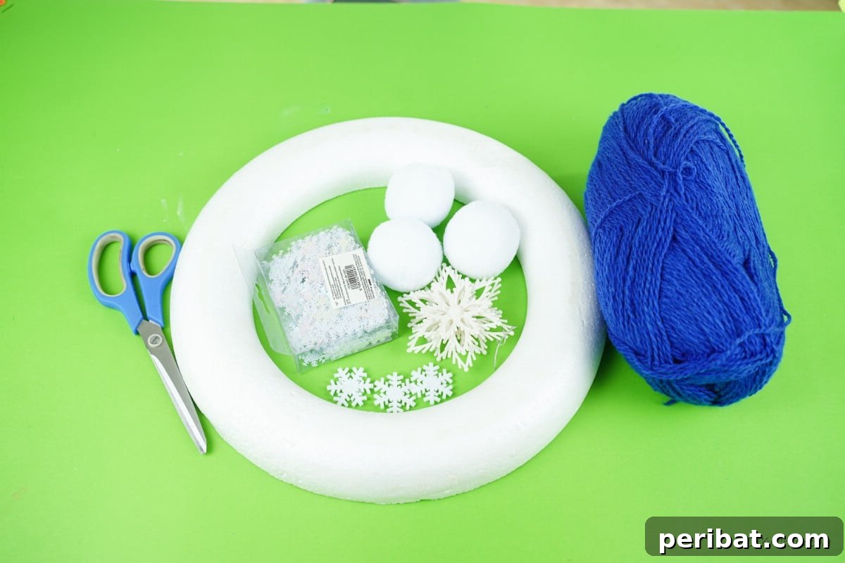 Glistening Snowflake Christmas Wreath 7 Array of craft supplies for wreath making including blue yarn, foam ring, cotton balls, and snowflake decorations, laid out neatly