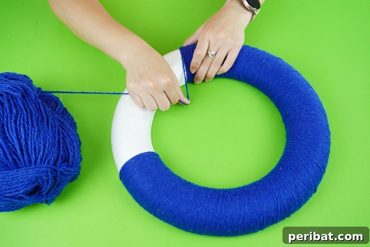 Glistening Snowflake Christmas Wreath 9 Blue yarn meticulously wrapped around a white foam ring, showing smooth, even coverage and preparation for decorations