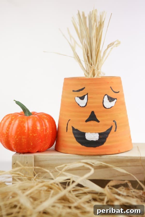 55+ Creative DIY Pumpkin Decorating Ideas for Fall 12 A whimsical smiling pumpkin planter, upcycled from a flower pot, displayed on a wooden crate