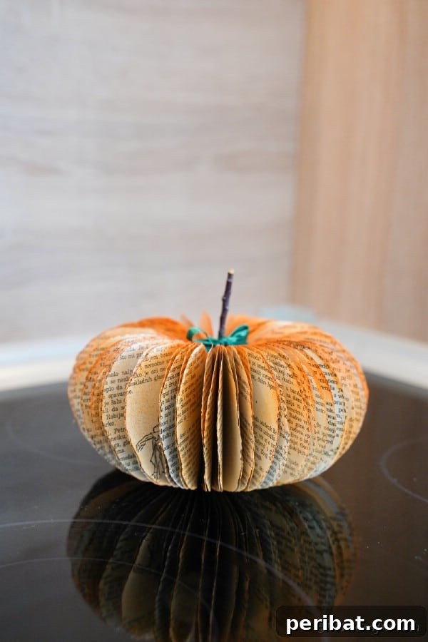 55+ Creative DIY Pumpkin Decorating Ideas for Fall 3 Charming old book page pumpkin on a weathered wooden table, ideal for rustic Fall decor
