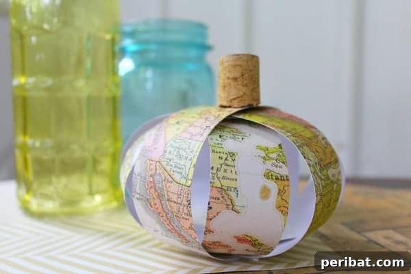 55+ Creative DIY Pumpkin Decorating Ideas for Fall 21 A unique upcycled paper map pumpkin adorned with a wine cork stem, displayed on a table