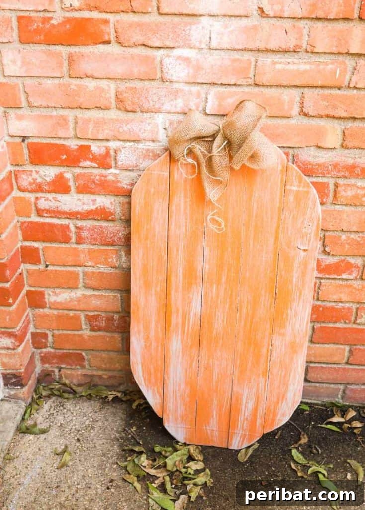 55+ Creative DIY Pumpkin Decorating Ideas for Fall 27 A charming DIY wood pumpkin resting against a rustic brick wall, ideal for Thanksgiving decor