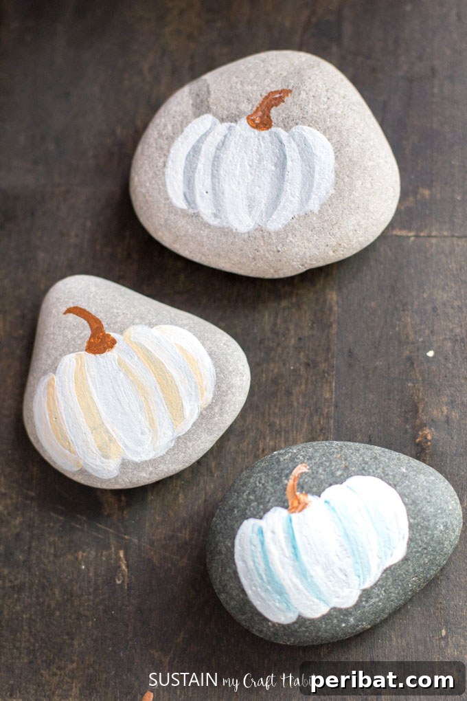 55+ Creative DIY Pumpkin Decorating Ideas for Fall 41 Rustic rocks painted with white pumpkins, offering a simple and earthy decoration