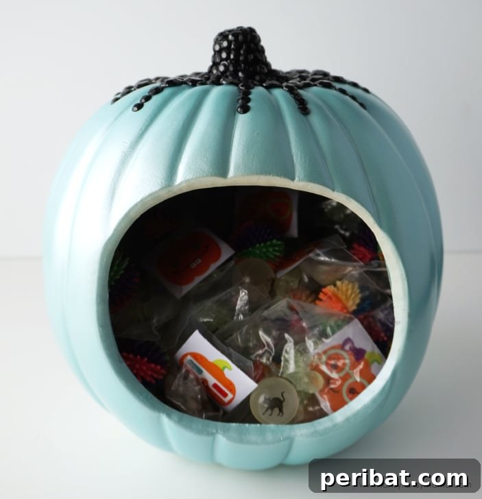 55+ Creative DIY Pumpkin Decorating Ideas for Fall 51 A friendly teal pumpkin treat jar filled with candy, promoting an inclusive Halloween