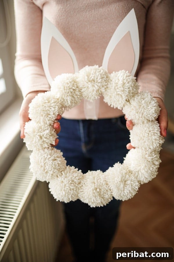 Sparking Joy: Easy Easter Crafts for Little Hands and Big Smiles 62 Woman holding easter pom pom wreath