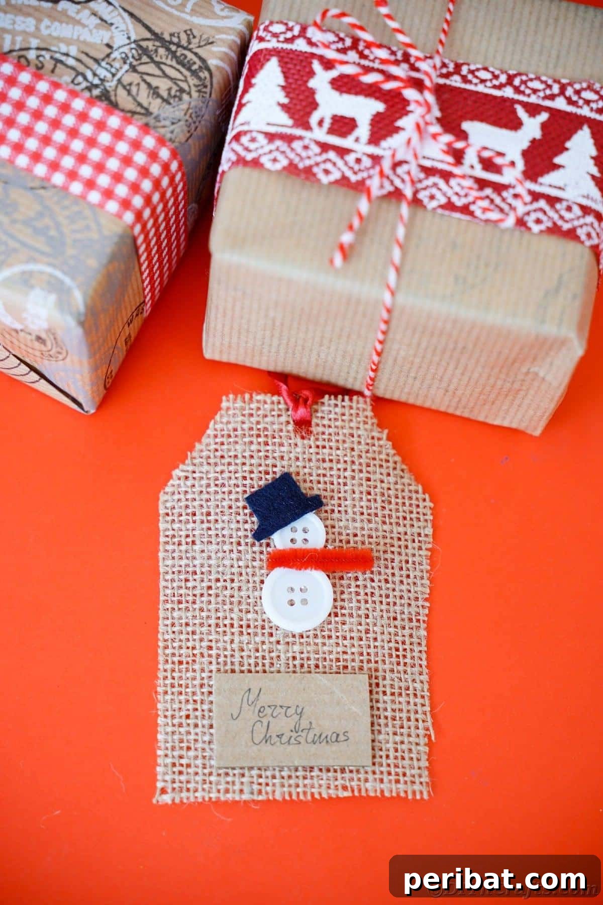 Charming Burlap Christmas Gift Tags: 3 Effortless DIY Styles 7 A snowman-themed gift tag crafted from burlap, resting on a vibrant red table beside a brown wrapped gift.