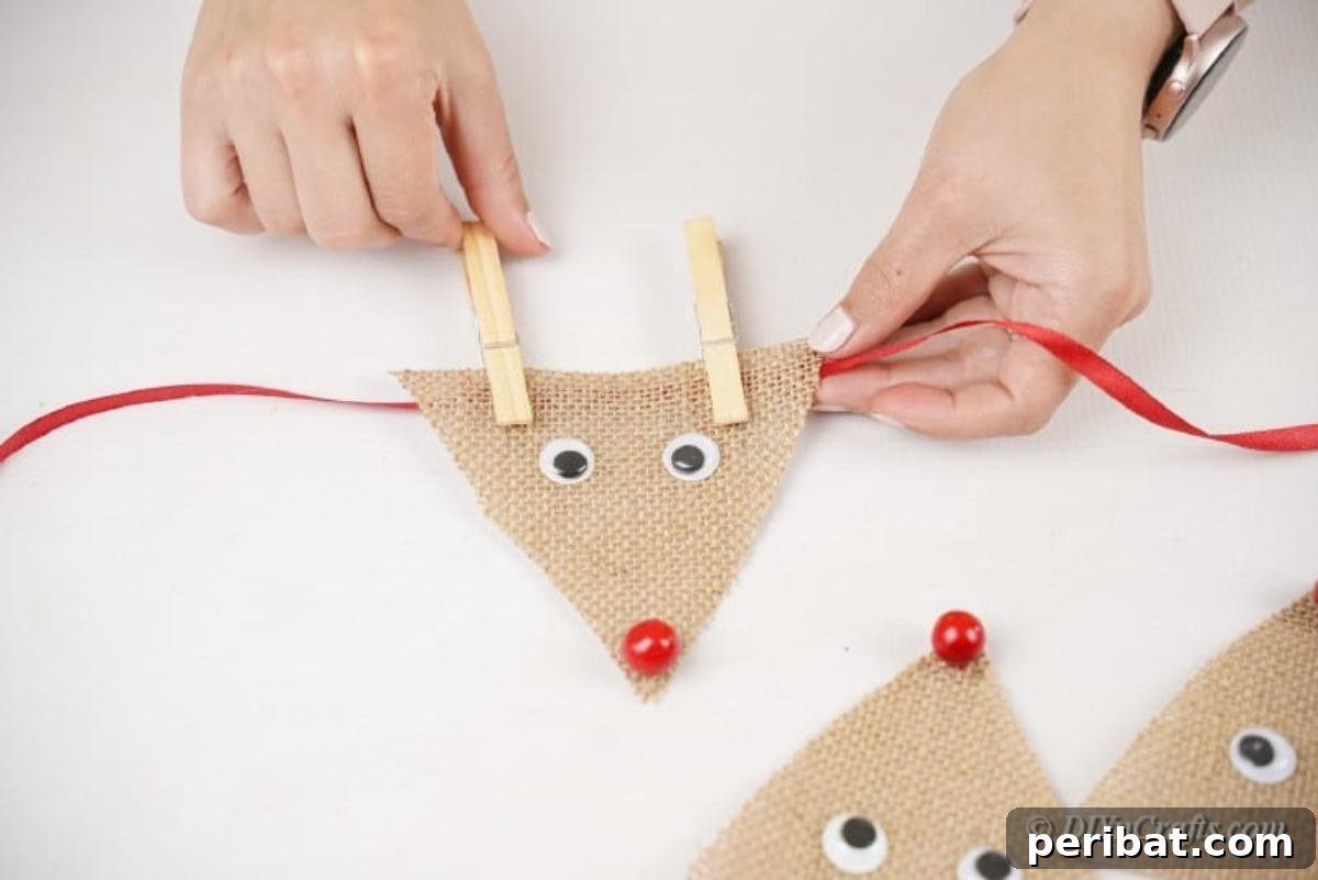 Rustic Reindeer Burlap Garland 10 Attaching a burlap reindeer to a ribbon with a clothespin