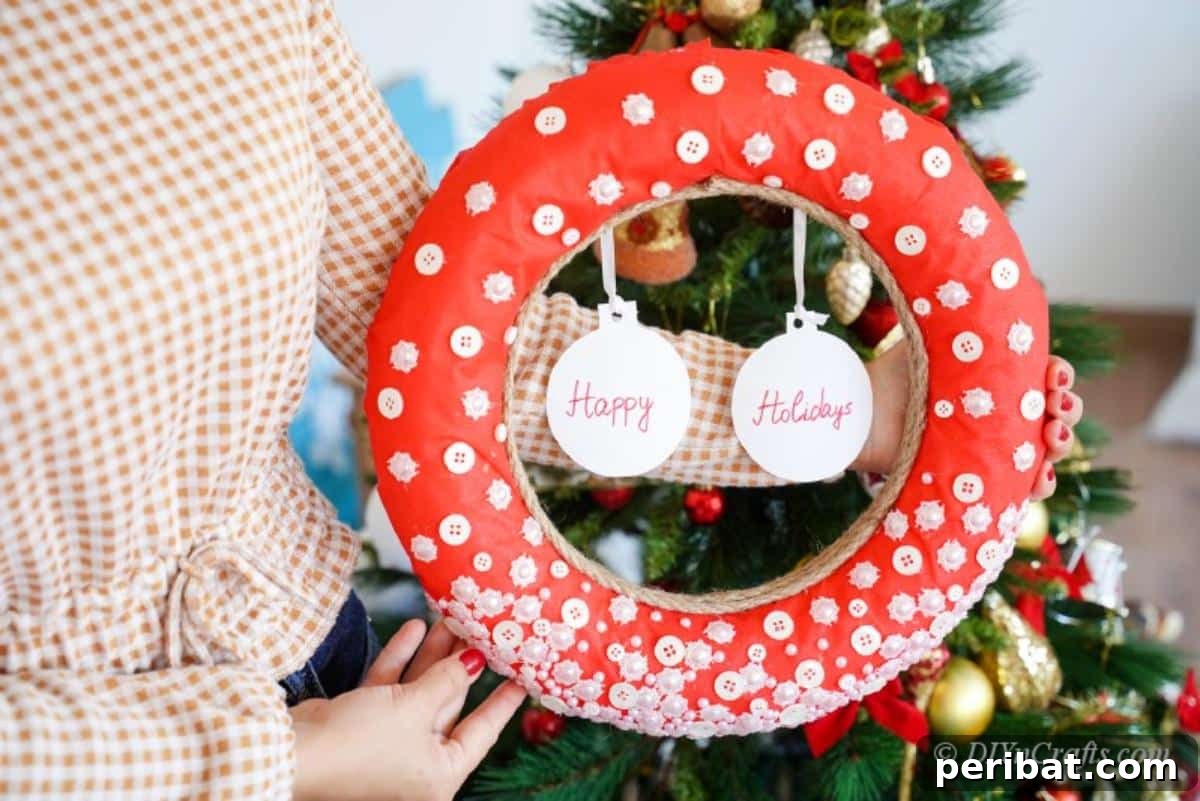 Woman holding a finished red button Christmas wreath, showcasing its intricate details