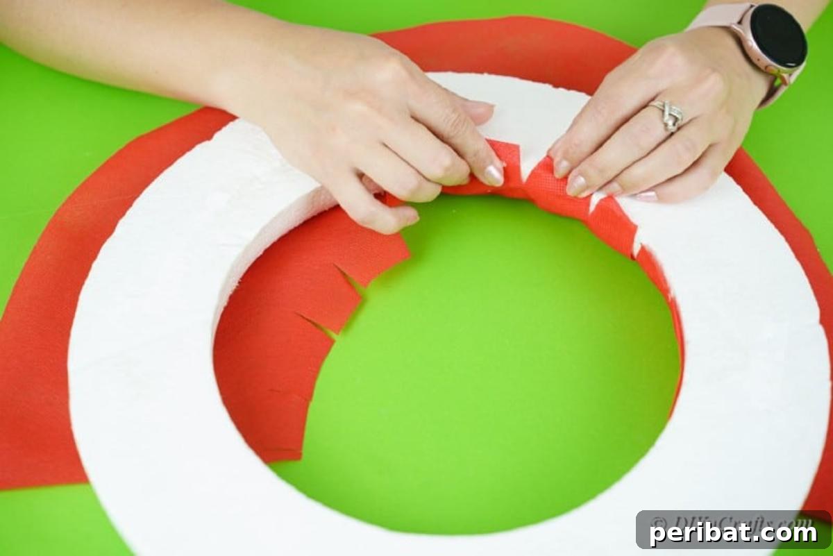 Applying wrapping paper to the foam ring with hot glue
