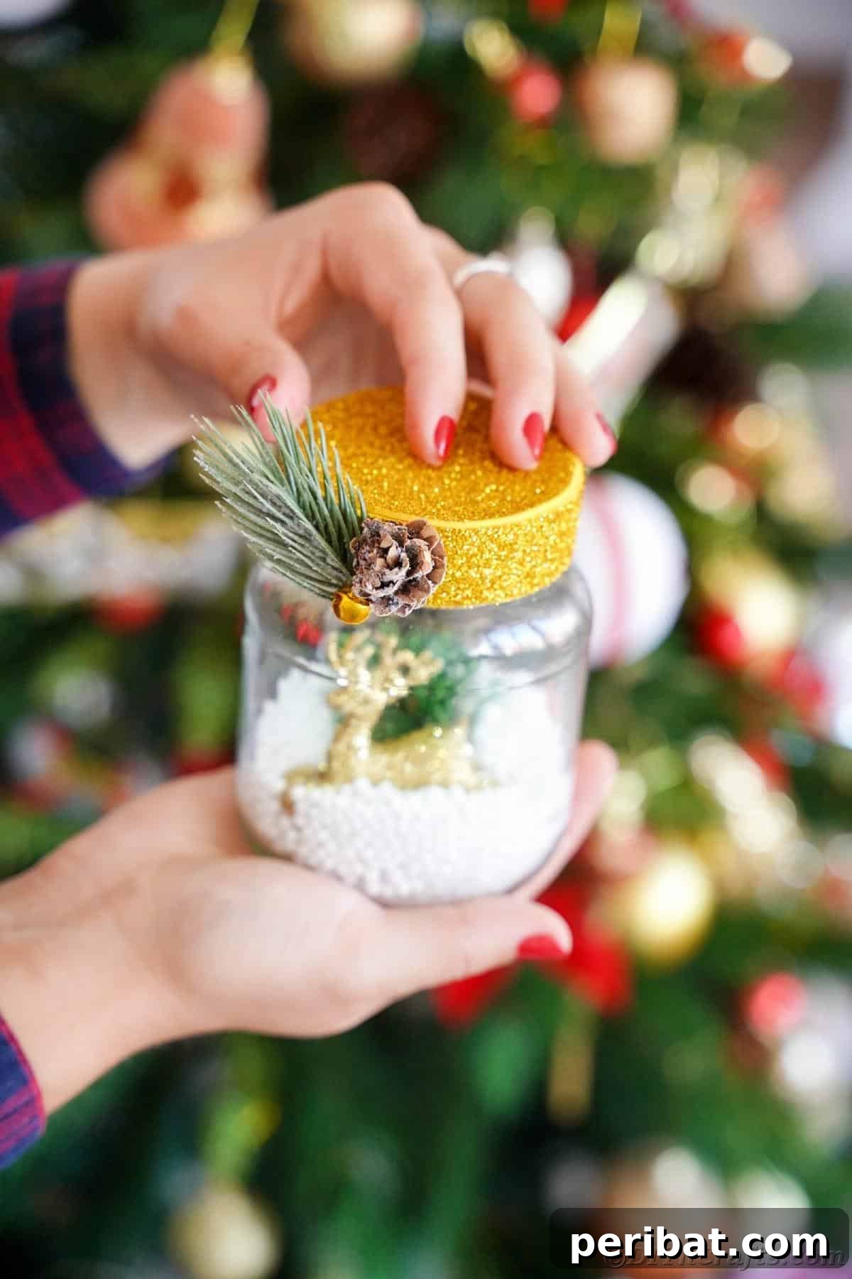 DIY Upcycled Christmas Snow Globe 5 Woman holding snow globe in front of christmas tree