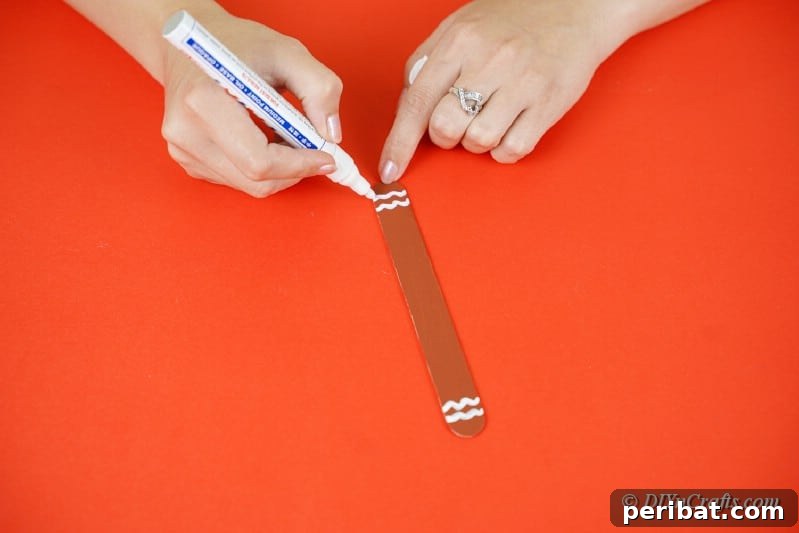 Sweet and Snowy Craft Stick Holiday Decor 19 Painting details onto a popsicle stick