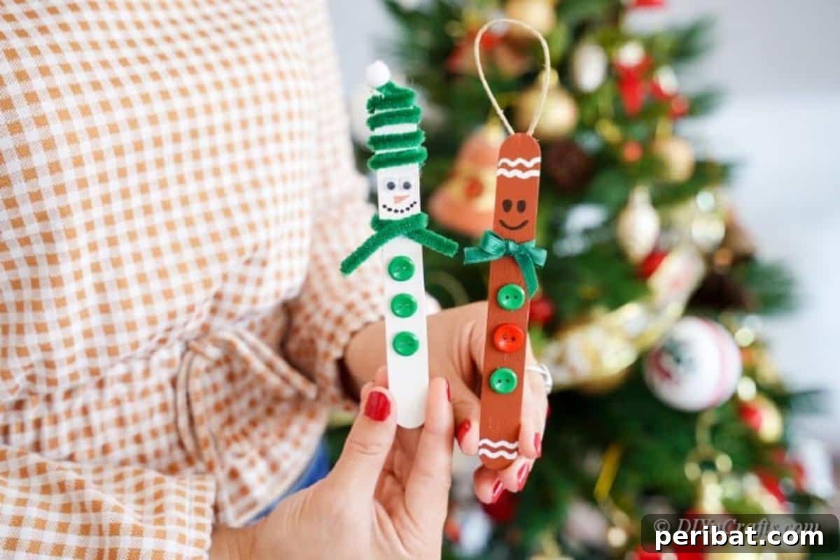 Sweet and Snowy Craft Stick Holiday Decor 3 Woman holding a finished popsicle stick snowman ornament in front of a decorated Christmas tree