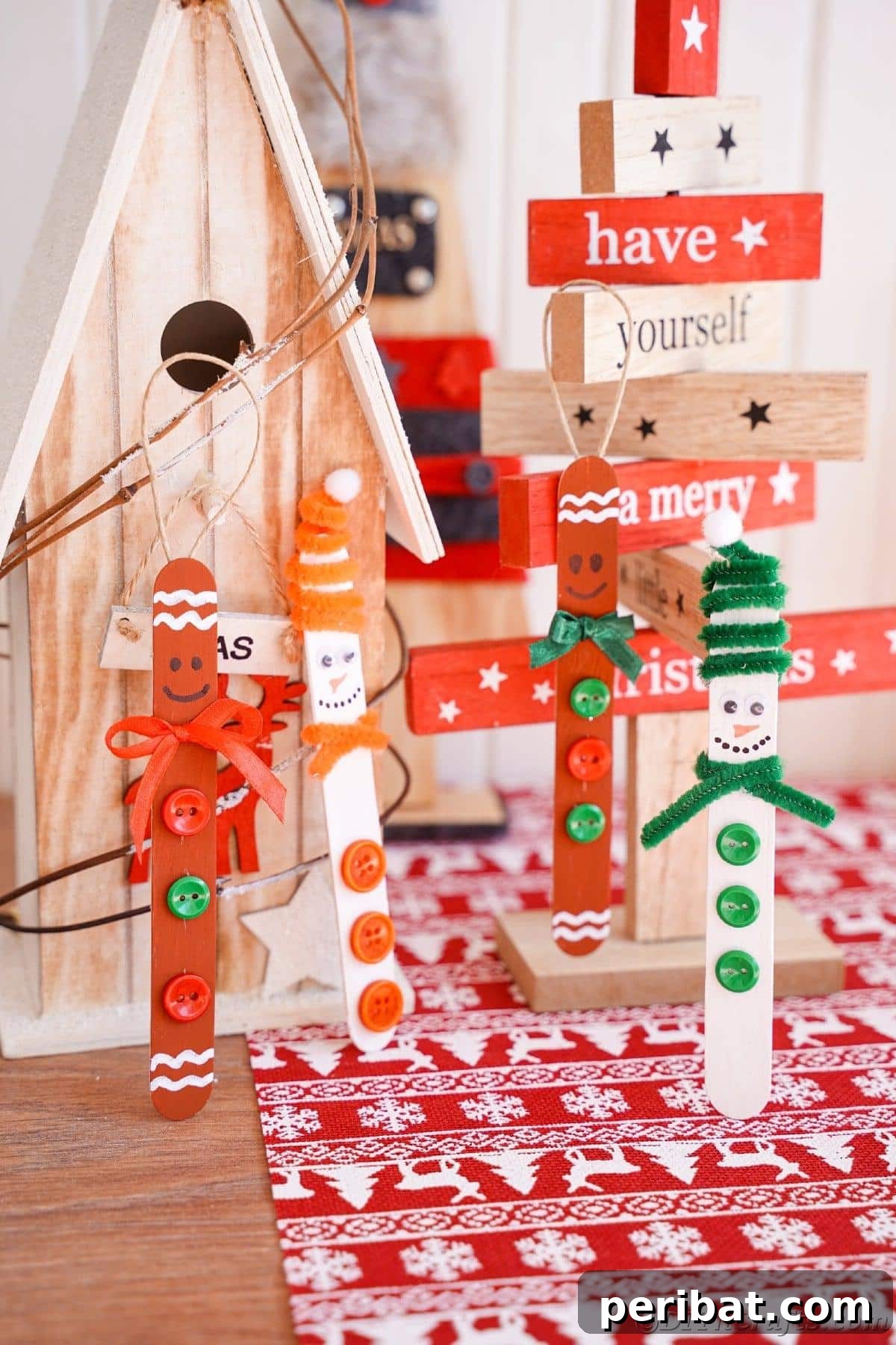 Sweet and Snowy Craft Stick Holiday Decor 7 Four decorated craft stick ornaments standing upright against wooden Christmas decorations