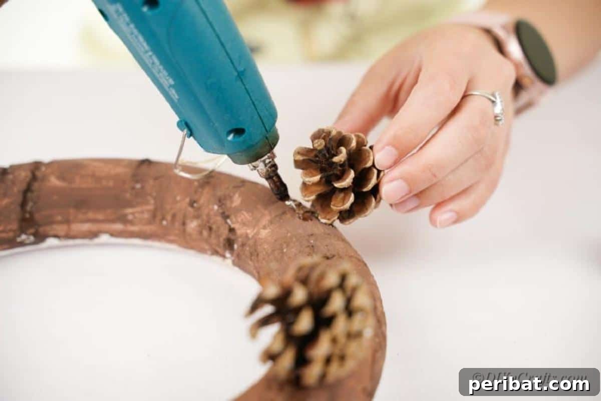 Foraged Fall Wreath 6 attatching pinecones to foam wreath