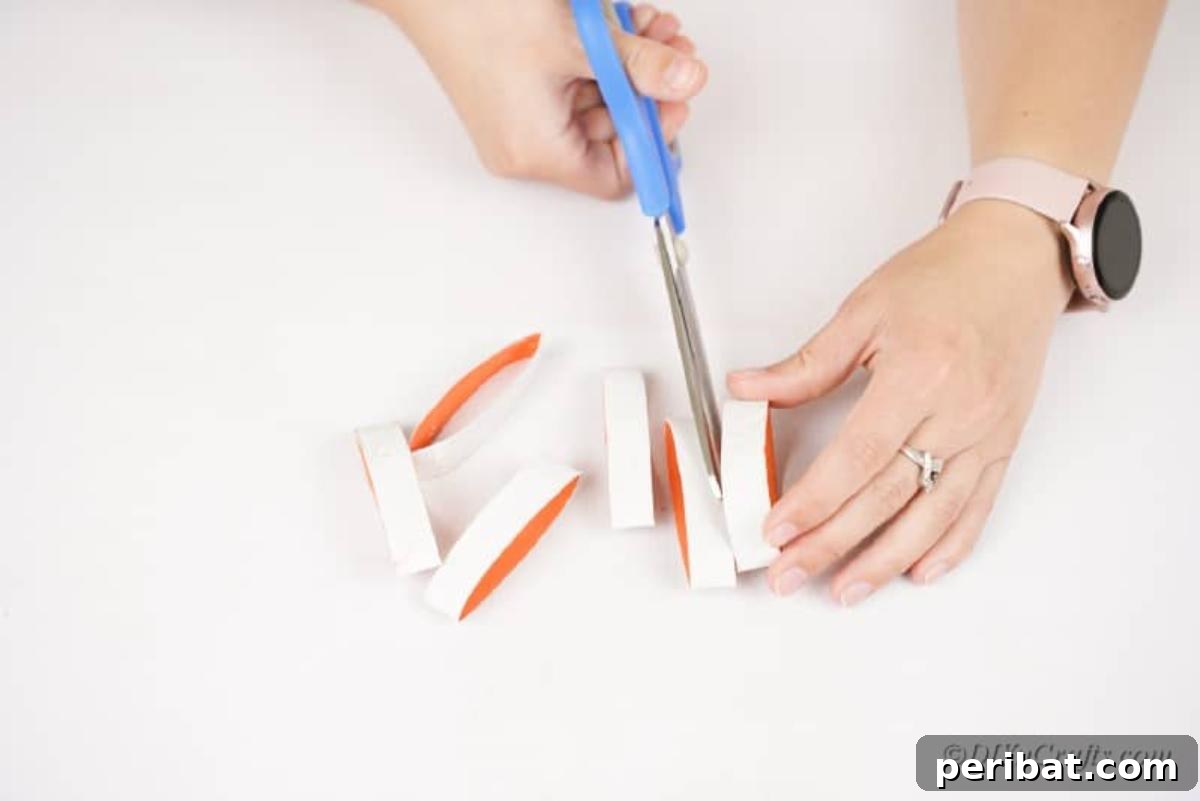 Cutting flattened toilet paper rolls into 1/2-inch strips with scissors.