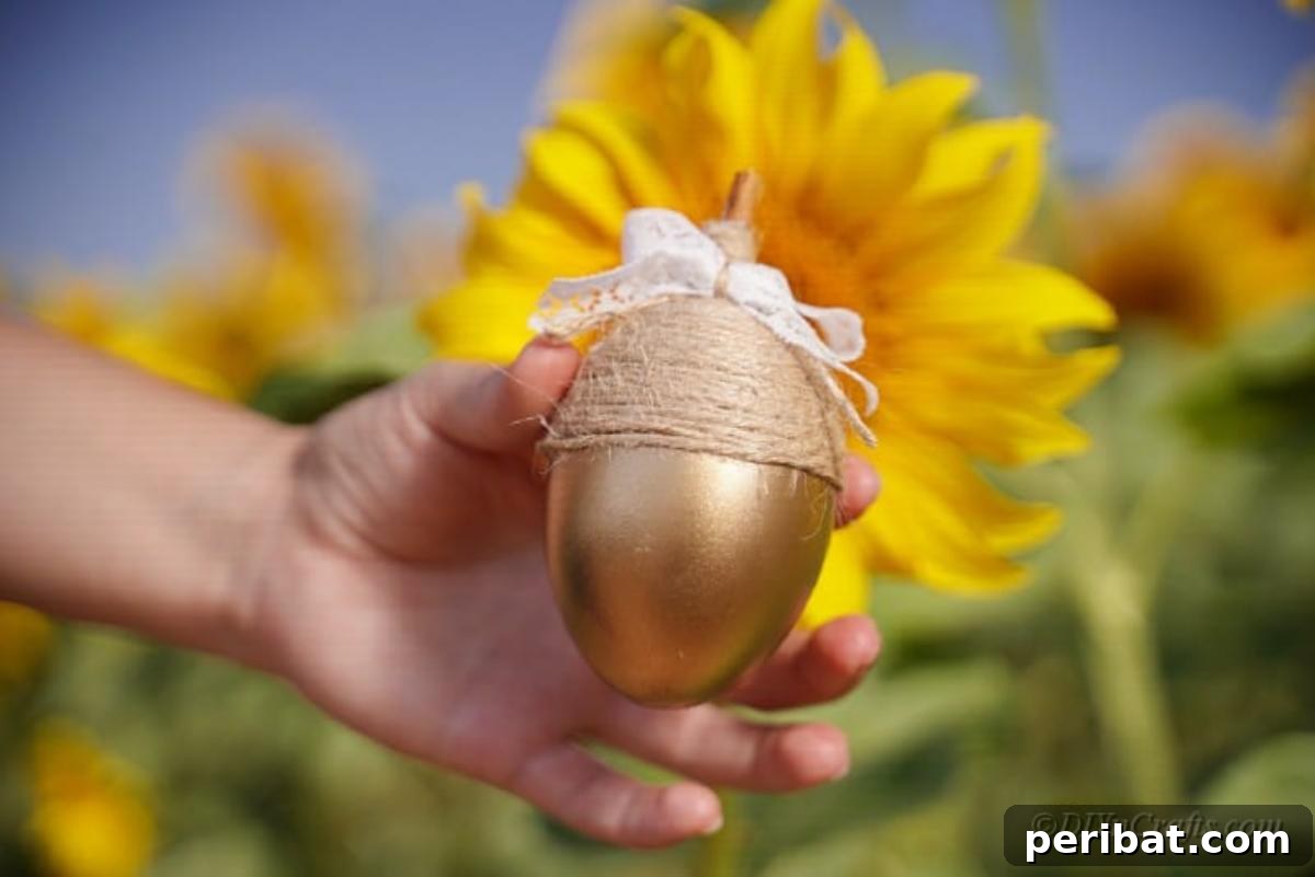 Atık Plastik Yumurtalardan Sonbahar Meşe Palamudu Yapımı 5 A finished golden craft acorn, elegantly displayed next to a vibrant sunflower outdoors, highlighting its natural inspiration.