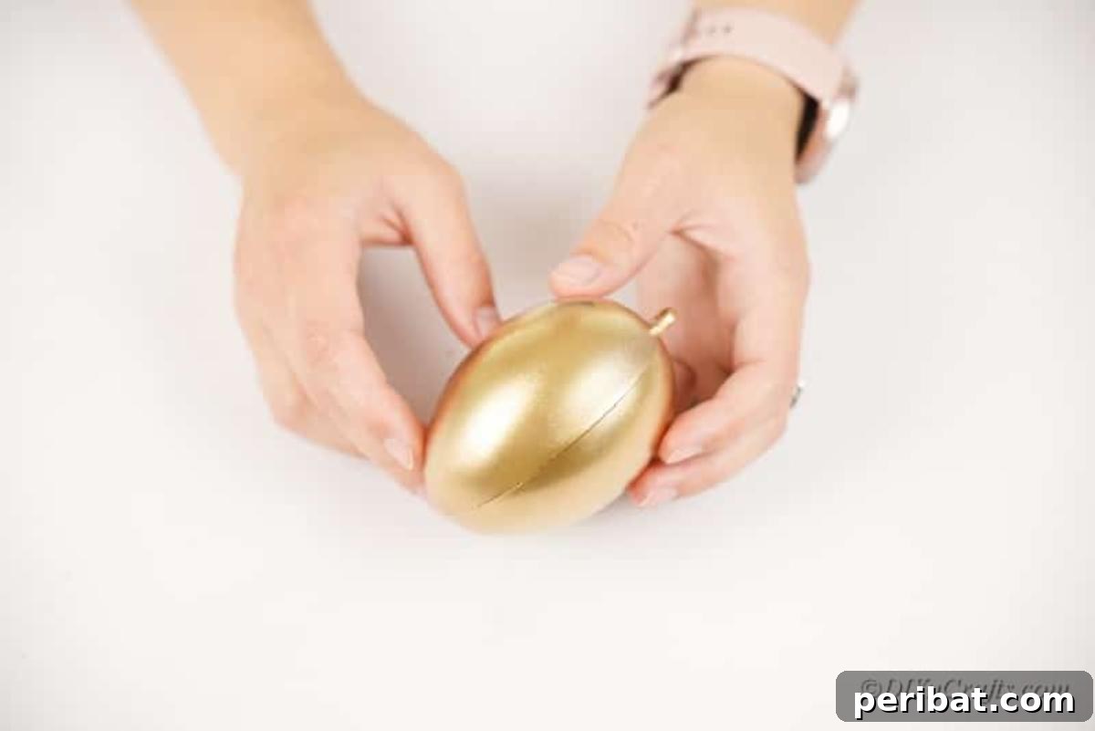 Atık Plastik Yumurtalardan Sonbahar Meşe Palamudu Yapımı 8 Assembling two golden spray-painted egg halves to create the core body of the decorative acorn.