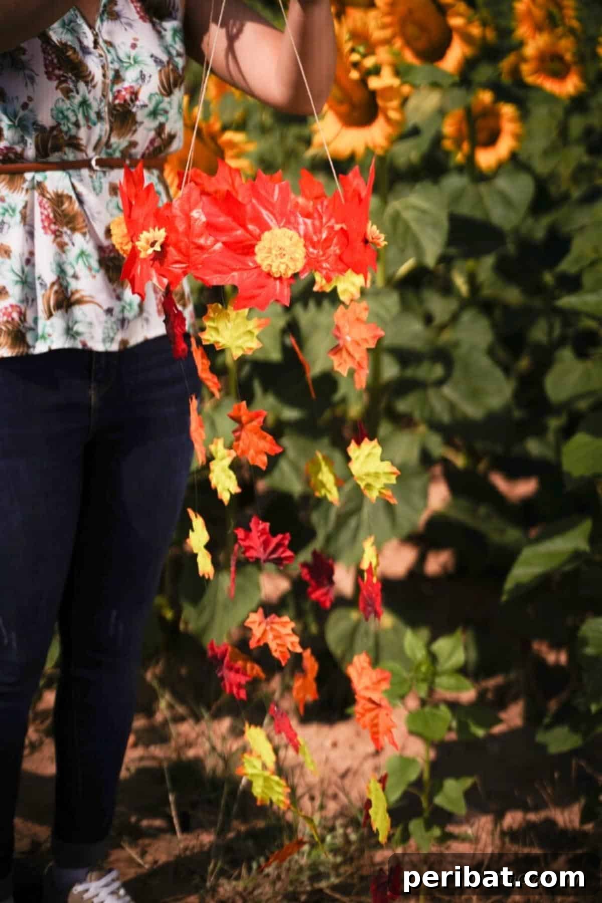 Vibrant Autumn Leaves Mobile 15 Woman in jeans holding fall leaf mobile in front of field of sunflowers
