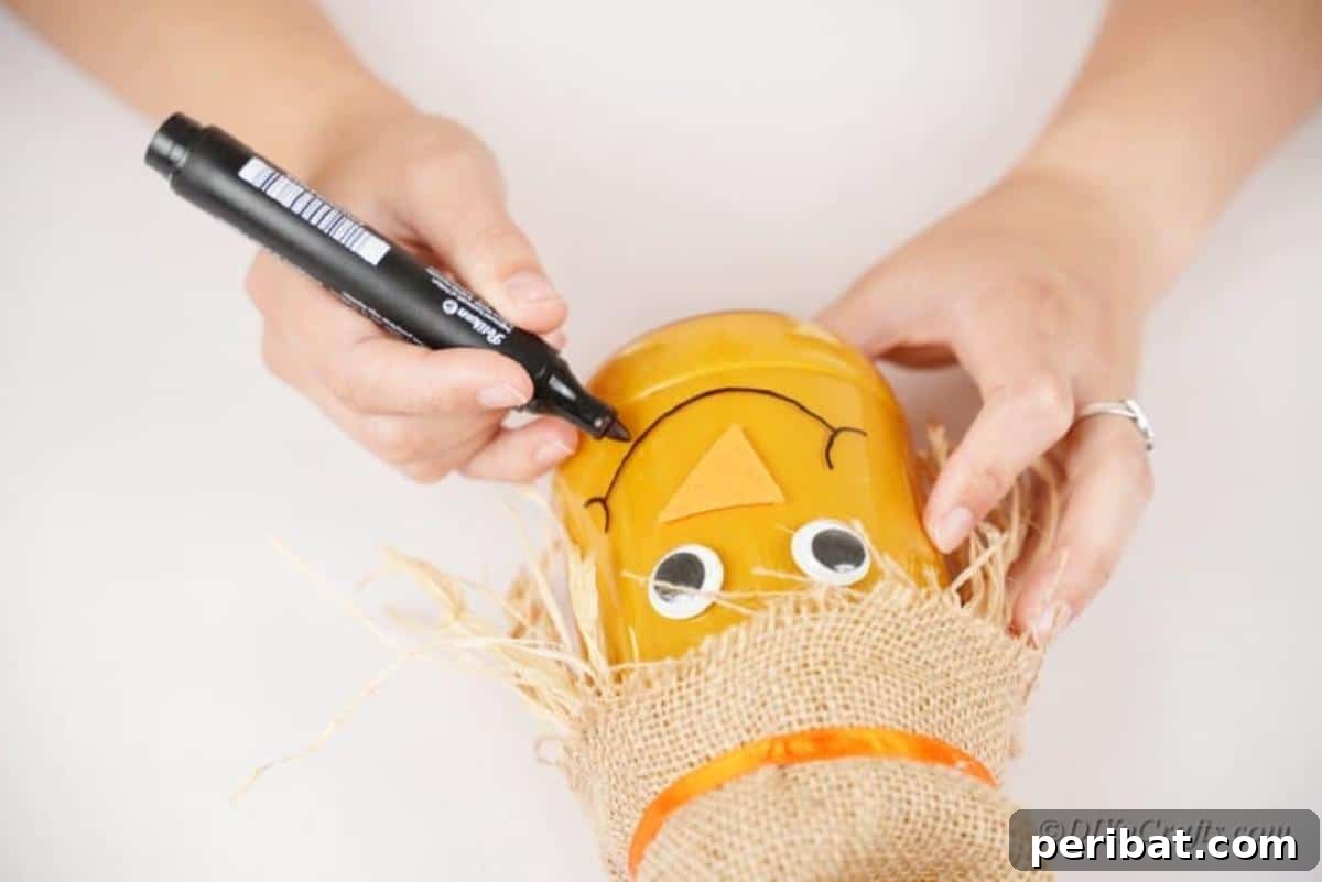 Whimsical Fall Scarecrow Jar Craft 15 A Sharpie marker draws a friendly, stitched smile onto the painted glass jar, giving the scarecrow craft its final adorable expression.