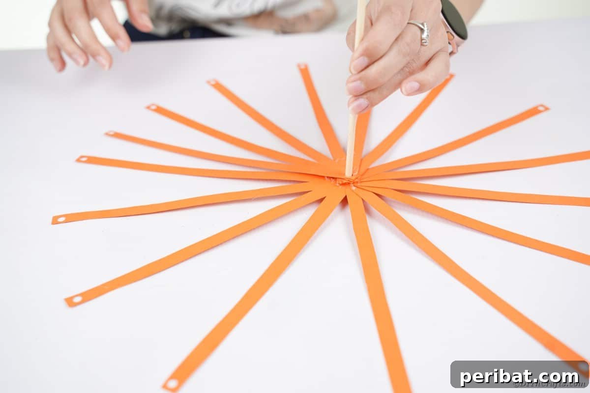 Spooky Paper Strip Creations: Bats, Pumpkins & Spiders 12 Numerous orange paper strips are fanned out and glued around the base of a dowel rod, forming a round shape.