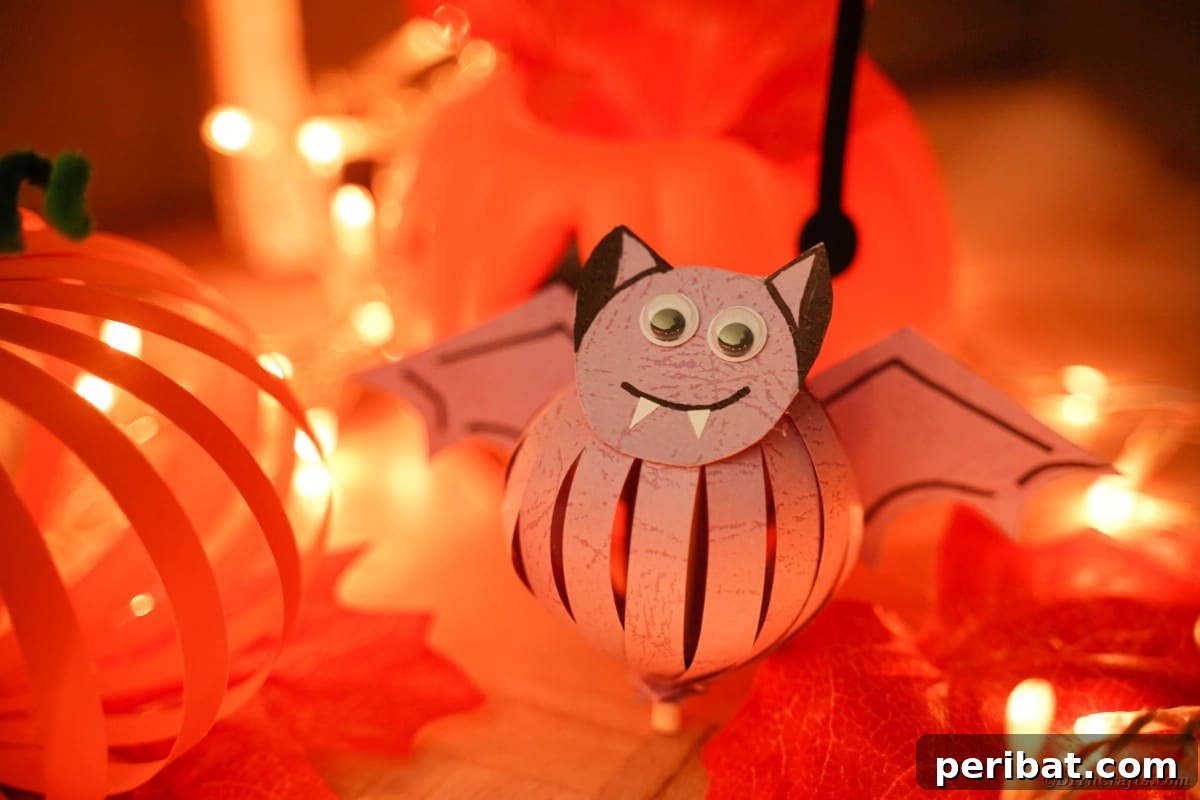Spooky Paper Strip Creations: Bats, Pumpkins & Spiders 4 An adorable purple paper bat with black outlined wings and cheerful googly eyes sits on a Halloween-themed table.