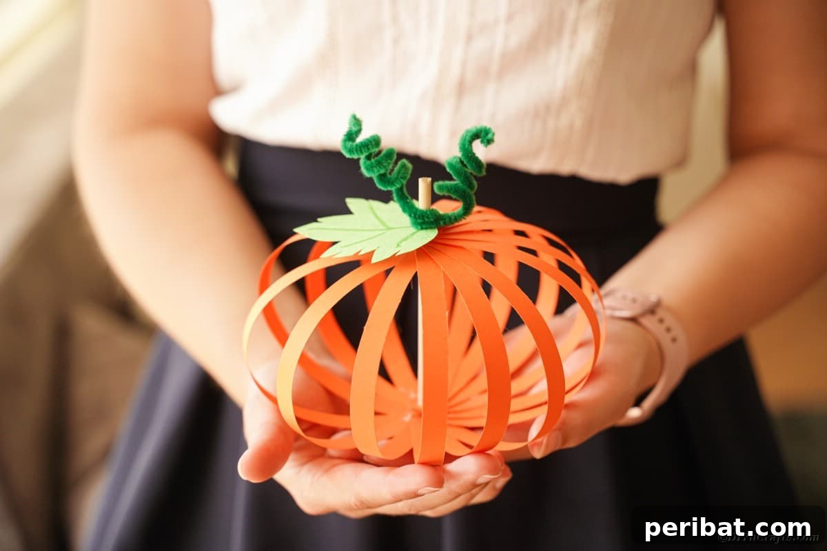 Spooky Paper Strip Creations: Bats, Pumpkins & Spiders 5 A woman's hands gently hold a finished paper strip pumpkin, showcasing the craft's simple beauty.