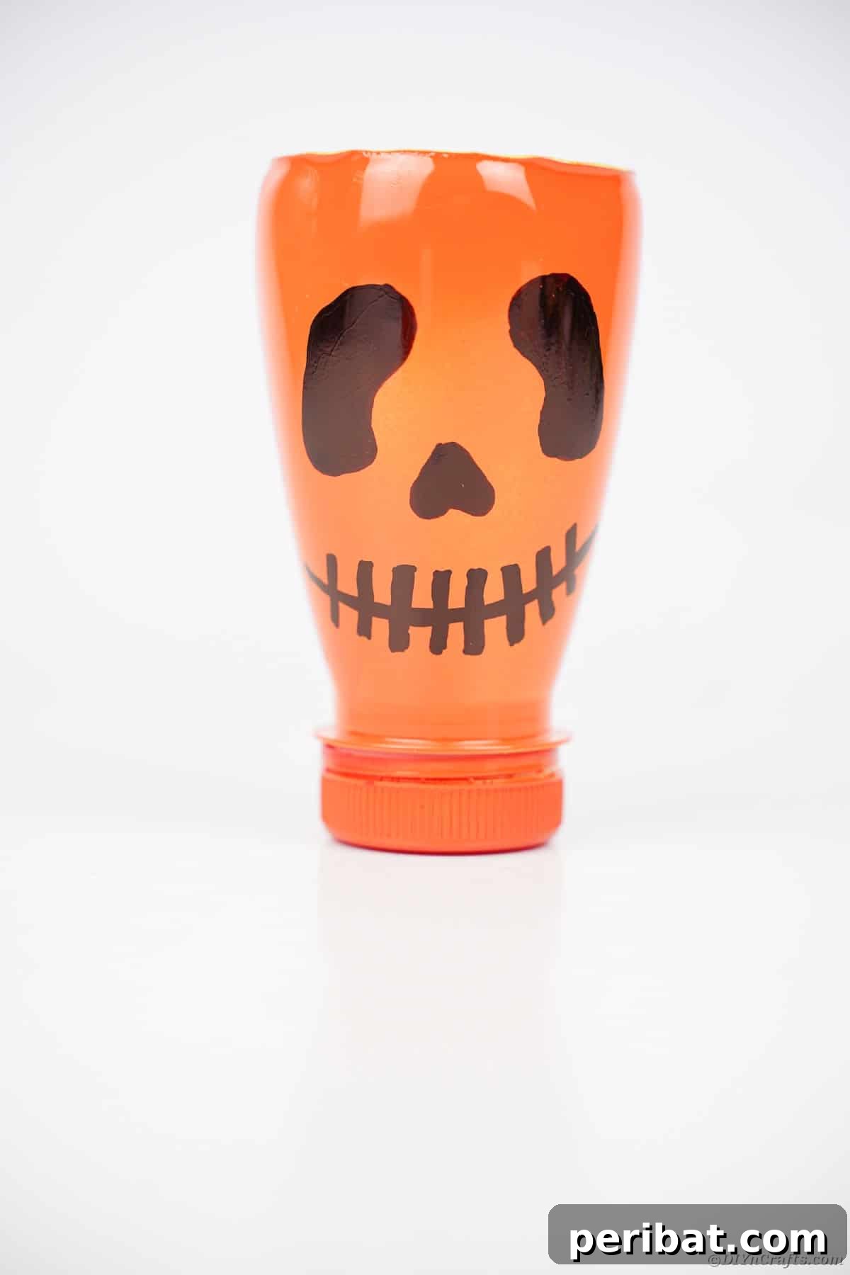 Charming Recycled Bottle Jack O Lantern 15 Upcycled pumpkin lantern with a friendly face on a white surface