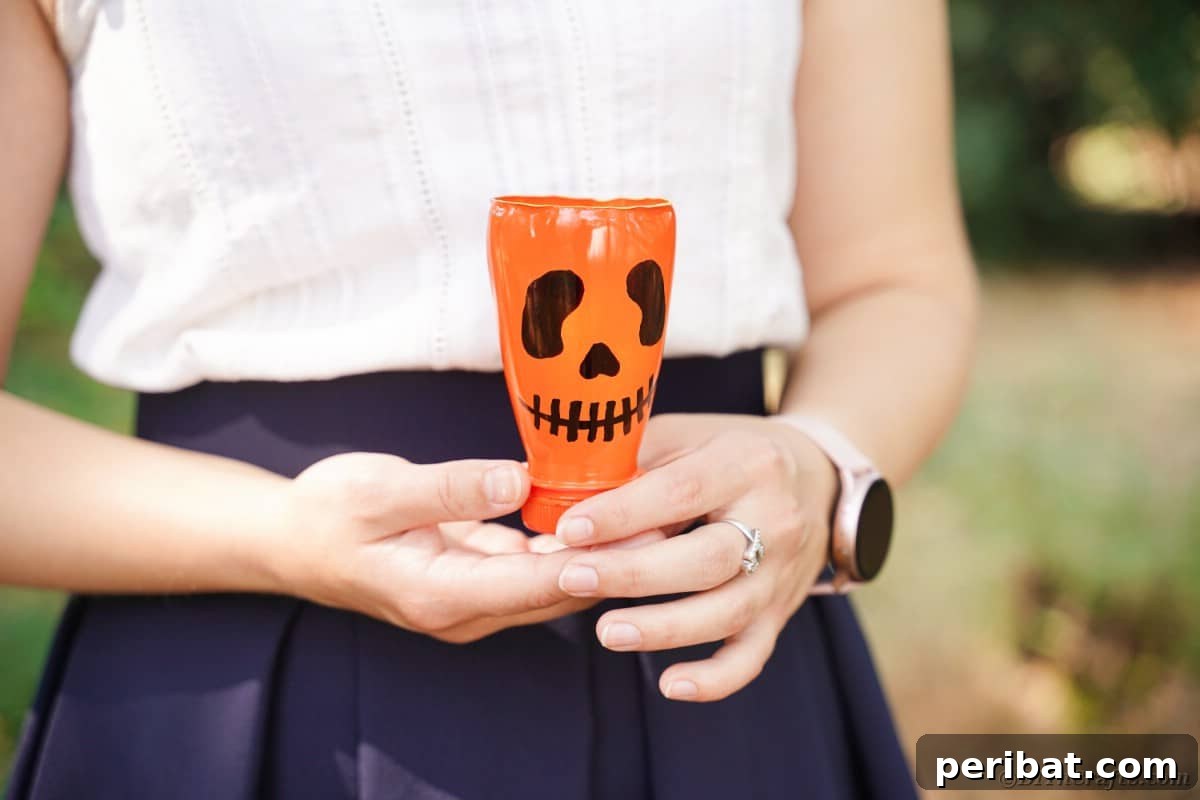 Charming Recycled Bottle Jack O Lantern 6 Person holding a finished pumpkin lantern, showcasing its warm glow