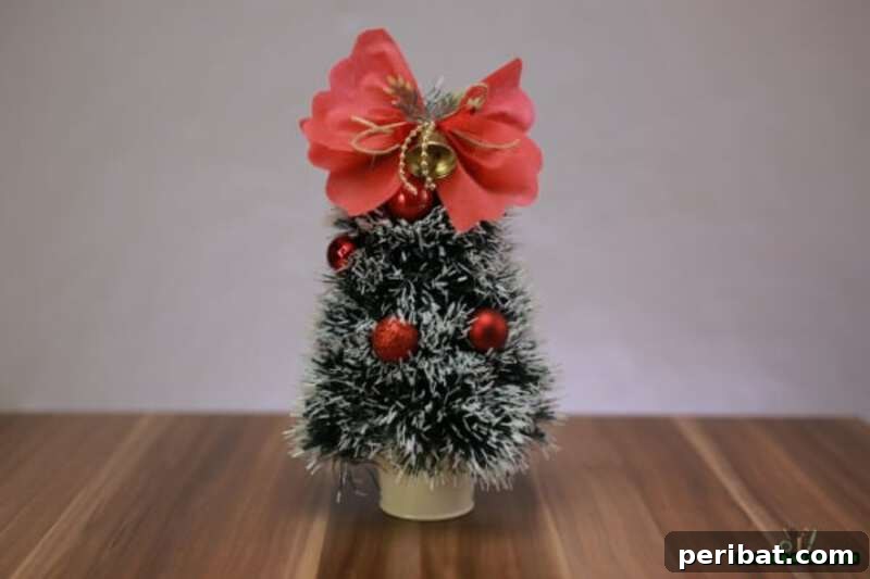 40+ Adorable Mini Christmas Tree Decor Ideas 13 Charming mini Christmas tree crafted from holiday garland, adorned with a festive bow, perfect for easy DIY decor.