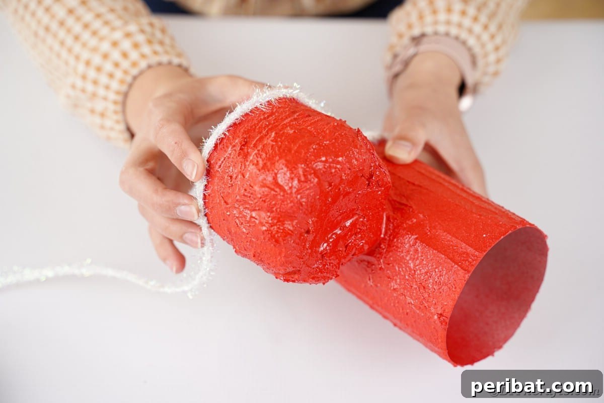 Gluing tinsel ribbon onto the base of the Santa boot.