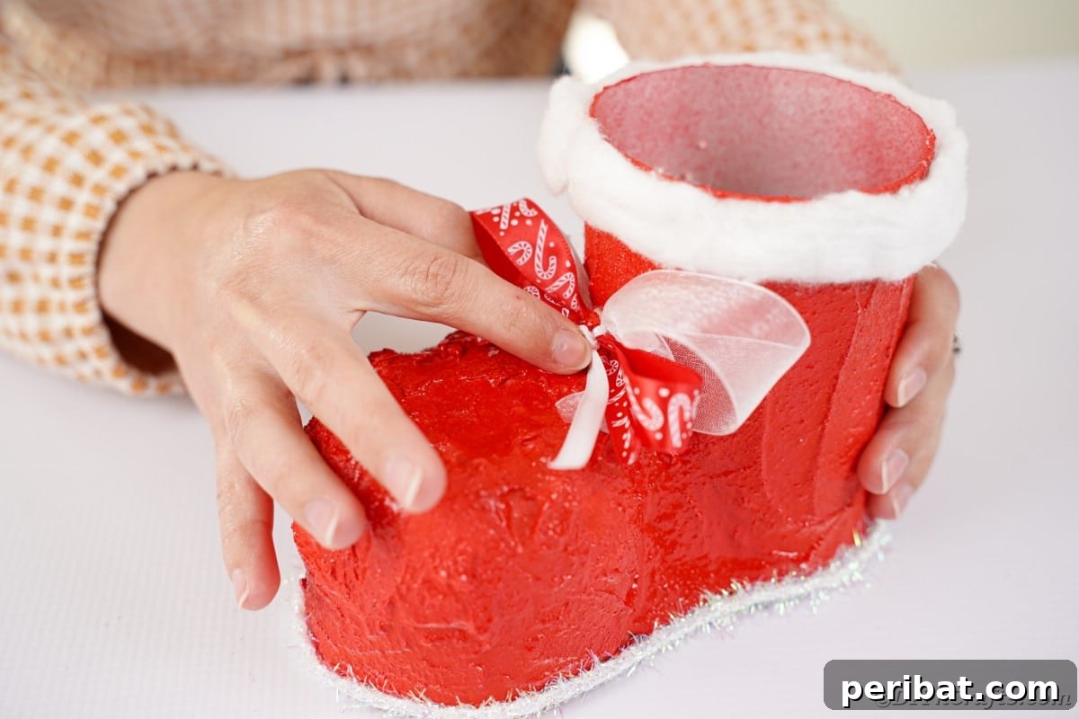 Gluing the completed ribbon bow onto the front of the Santa boot.