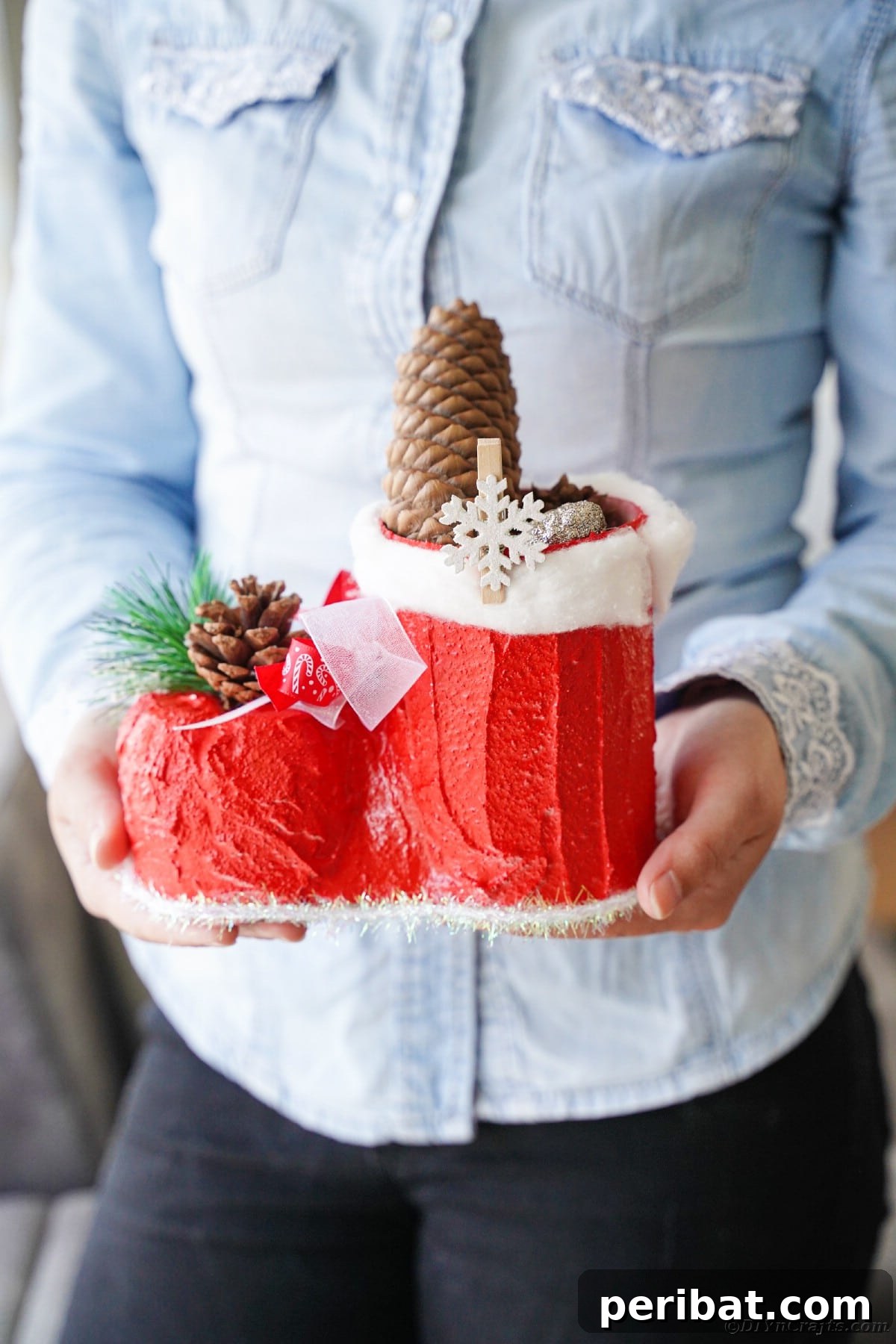 A woman proudly showcasing her finished Santa boot craft, holding it for display.