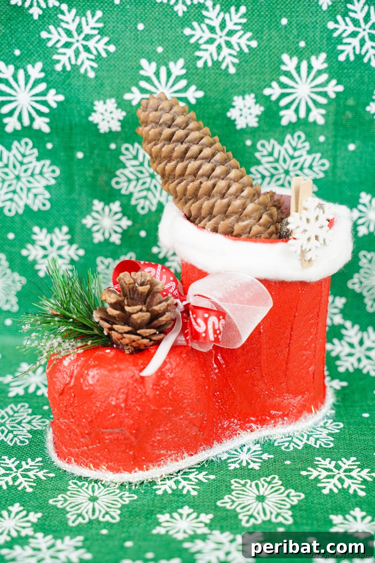 A beautifully decorated Santa boot resting on festive green holiday paper.