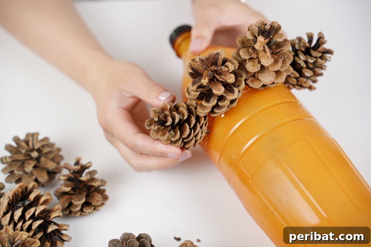 Charming Upcycled Pinecone Hedgehog Art 11 Gluing pinecones onto the orange bottle, building the hedgehog's spiky exterior
