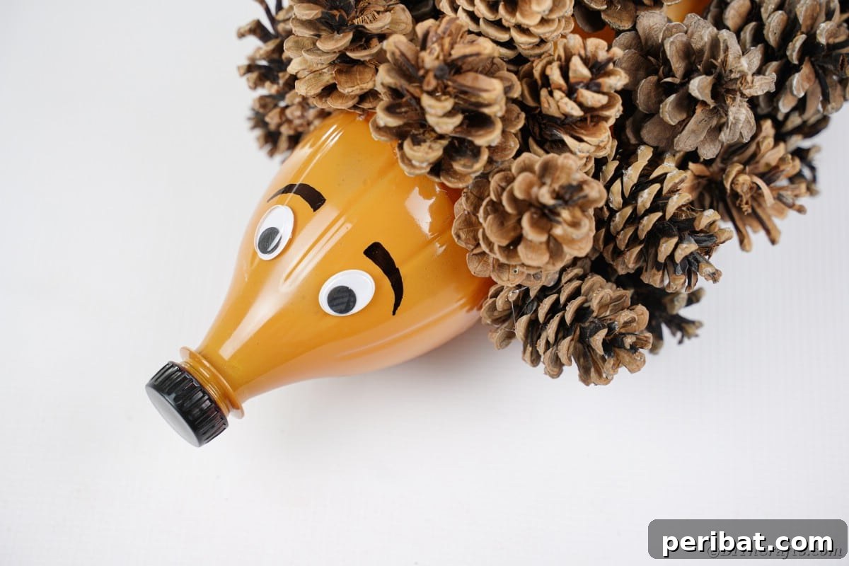 Charming Upcycled Pinecone Hedgehog Art 14 Finished pinecone hedgehog on a white surface, showcasing the added eyebrows and facial details