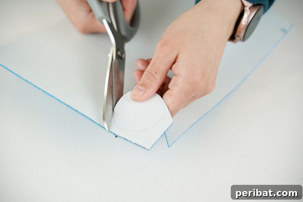DIY Painted Tin Can Snowman Video Tutorial 11 Hands carefully cutting a circular shape from foam paper, demonstrating precision in crafting the snowman's hat.