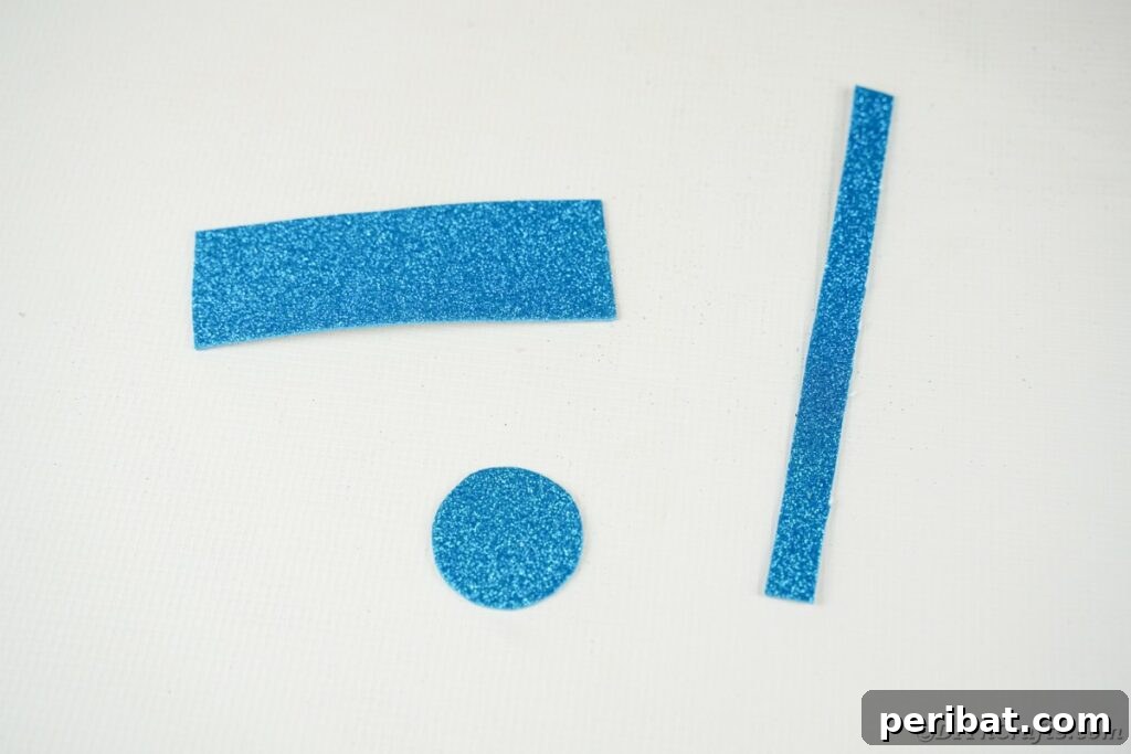 DIY Painted Tin Can Snowman Video Tutorial 12 Precisely cut strips of blue foam paper laid out on a white table, prepared for crafting the snowman's top hat.
