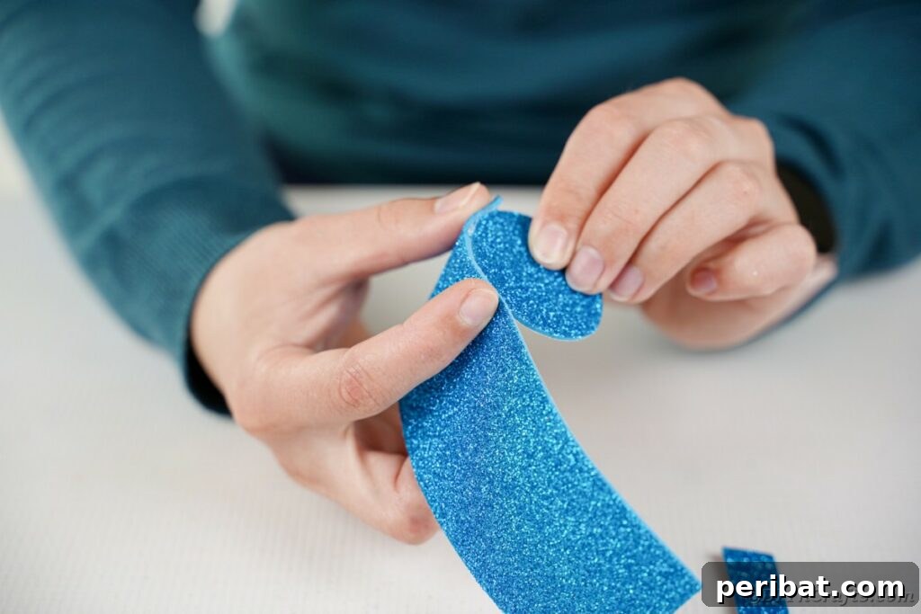 DIY Painted Tin Can Snowman Video Tutorial 13 A person meticulously gluing a strip of foam paper around the edge of a foam circle to construct the top portion of a snowman's hat.